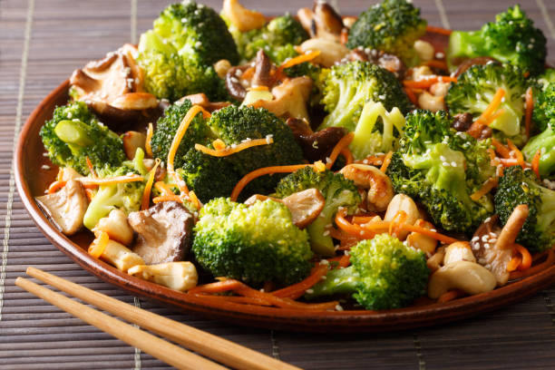 serving of fried broccoli with shiitake, carrots and cashew nuts close-up in a plate. horizontal - edible mushroom shiitake mushroom fungus chinese cuisine imagens e fotografias de stock