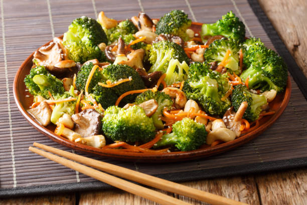 roasted broccoli salad with shiitake, carrots and cashew nuts close-up in a plate. horizontal - edible mushroom shiitake mushroom fungus chinese cuisine imagens e fotografias de stock