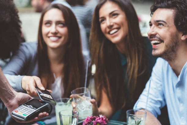 istock Friends in bar paying contactless 1208191590