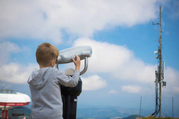 istock Little boy looking the sky through coin operated binoculars. 1208193731