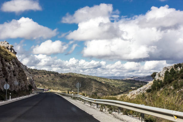 istock Lonely and moody road with clouds and an interesting light. Mountain road with dramatic colourful sky. Journey, outdoor, travel concept. 1208196354