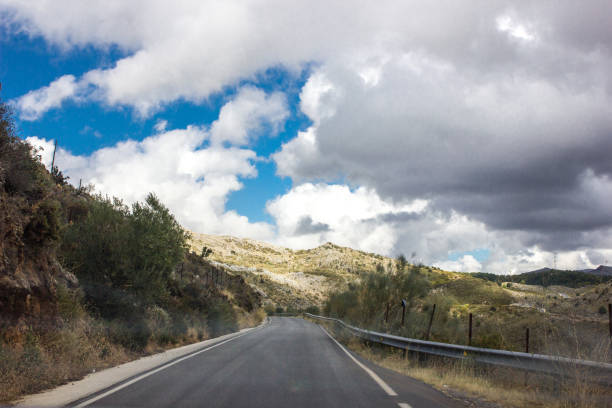istock Lonely and moody road with clouds and an interesting light. Mountain road with dramatic colourful sky. Journey, outdoor, travel concept. 1208196365