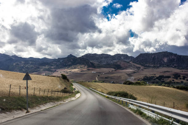 istock Lonely and moody road with clouds and an interesting light. Mountain road with dramatic colourful sky. Journey, outdoor, travel concept. 1208196392