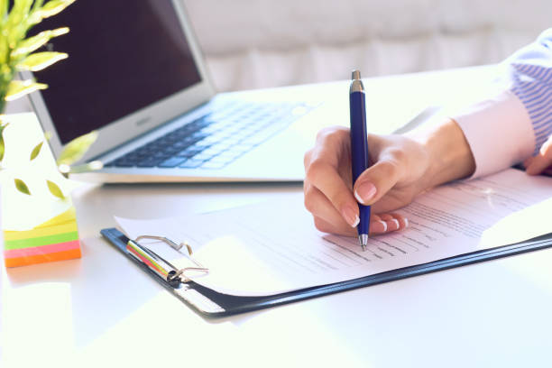 istock Businesswoman sitting at office desk signing a contract or making notes. 1208196804