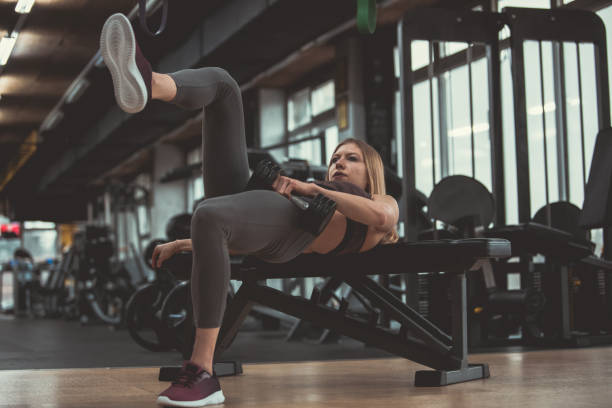 istock Athletic woman focusing in doing glute bridge with dumbbell 1208199751