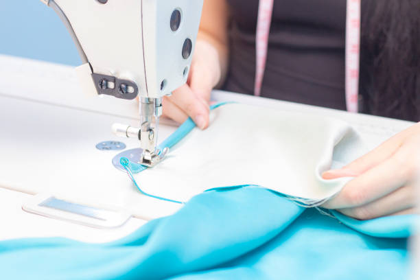 istock sewing Studio. seamstress sewing on a sewing machine close-up. A set of items for needlework: threads, needles, pins, scissors, tape measure, etc. 1208203312