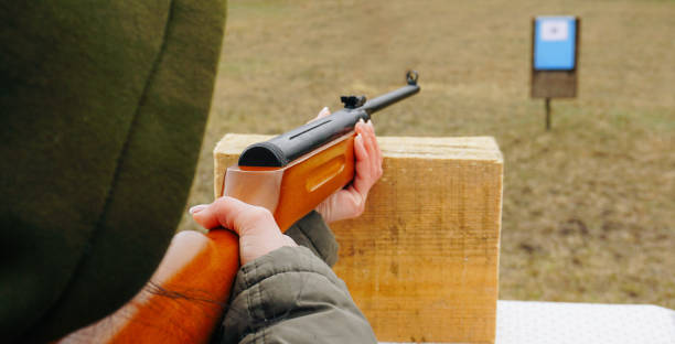 девушка-стрелок стреляет из винтовки в цель - rifle sport air target shooting стоковые фото и изображения