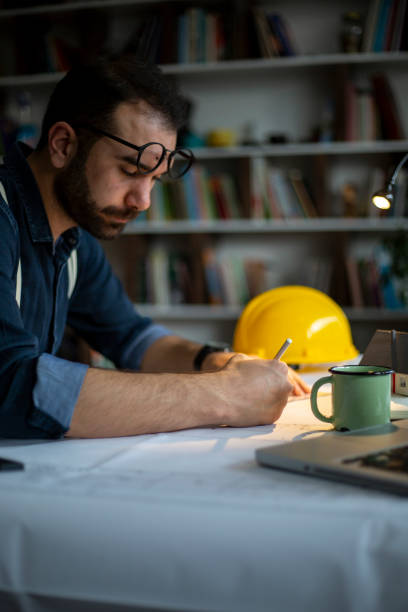 istock Architect working with blueprints in the home office. 1208204696
