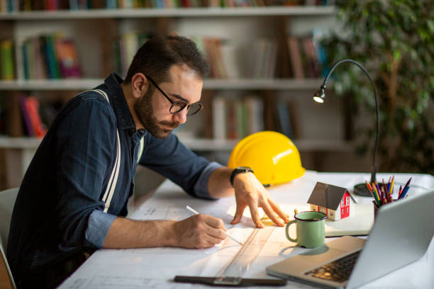 istock Architect working with blueprints in the home office. 1208205414