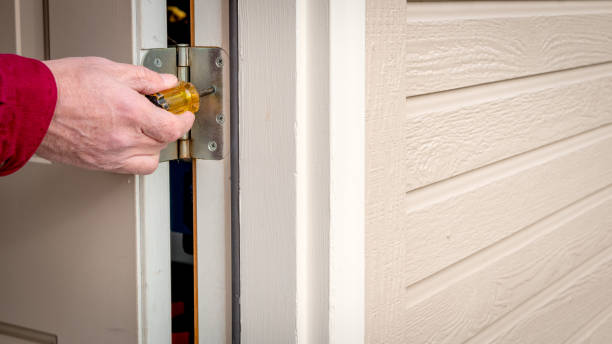 istock Handy man works on tightening a hinge on a back door 1208205506