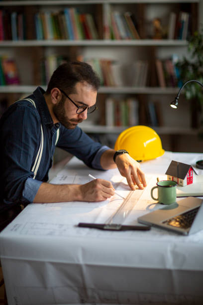 istock Architect working with blueprints in the home office. 1208205617