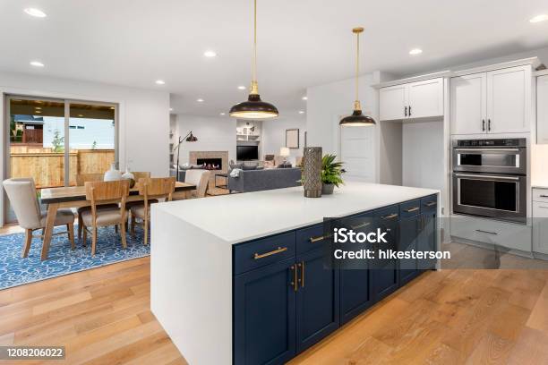 Beautiful Kitchen In New Luxury Home With Large Island Pendant Lights And Hardwood Floors Shows Dining Area And Living Room Stock Photo - Download Image Now