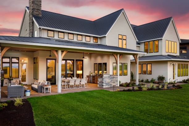 Beautiful luxury home exterior at sunset, featuring large covered patio with outdoor kitchen and barbecue facade of home with manicured lawn and large covered patio patio photos stock pictures, royalty-free photos & images