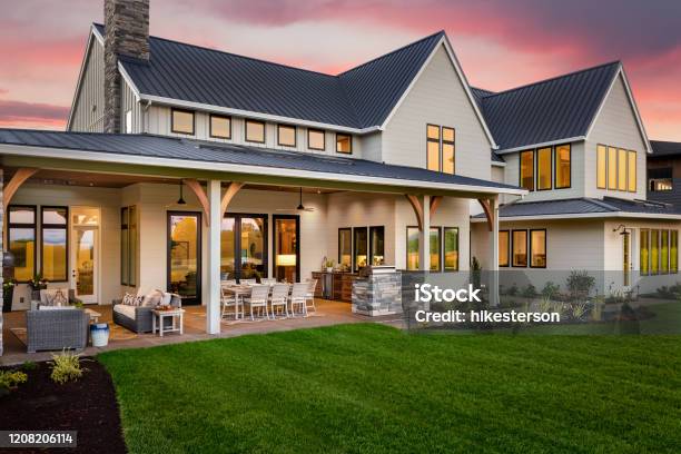 Beautiful Luxury Home Exterior At Sunset Featuring Large Covered Patio With Outdoor Kitchen And Barbecue Stock Photo - Download Image Now