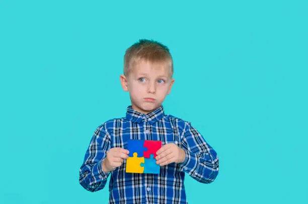 Photo of A little child holding a puzzle symbol of Public awareness for autism spectrum disorder. World Autism Awareness Day.