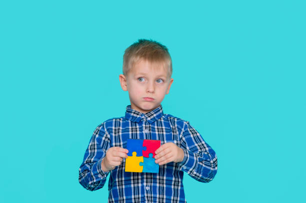 małe dziecko trzymające symbol układanki świadomości społecznej zaburzeń ze spektrum autyzmu. światowy dzień świadomości autyzmu. - developmental zdjęcia i obrazy z banku zdjęć