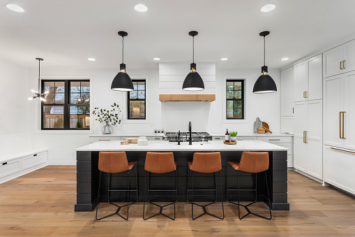 Hermosa cocina blanca con acentos oscuros en la nueva casa de lujo estilo farmhouse photo