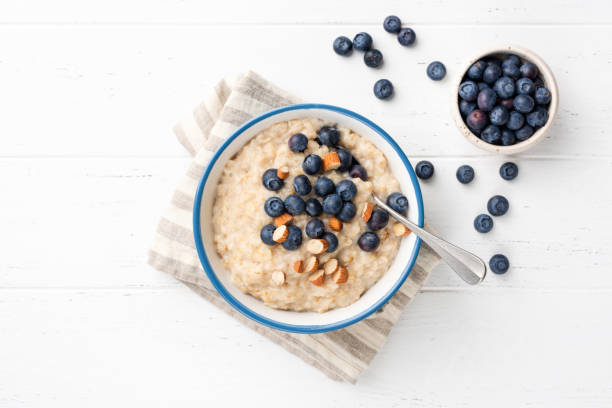 porridge di farina d'avena con mirtilli, mandorle in ciotola - porridge foto e immagini stock