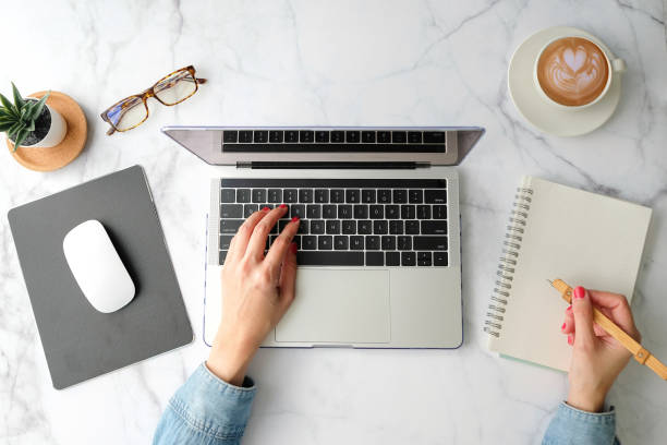 flat lay workspace. woman hand with coffee cup, smartphone, computer, notebook, planner and stationary with copy space on marble table background. top view. modern style. - contemporary laptop human hand computer keyboard imagens e fotografias de stock