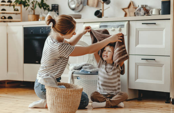 feliz familia madre ama de casa y el niño en la lavandería con lavadora - stereotypical housewife little girls family domestic kitchen fotografías e imágenes de stock