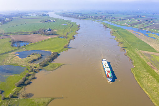 Inland container barge on River Lek aerial view near the village of Ravenswaaij, Gelderland, Netherlands