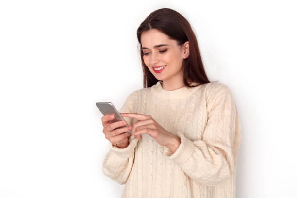 istock Young woman studio standing isolated on white checking media on smartphone joyful 1208214810