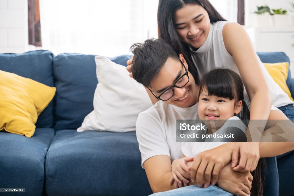 Portrait of happy Asian family spending time together on sofa in living room. family and home concept. Family Stock Photo