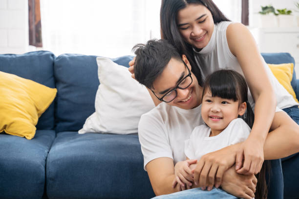 Portrait of happy Asian family spending time together on sofa in living room. family and home concept. Portrait of happy Asian family spending time together on sofa in living room. family and home concept. family asian ethnicity couple child stock pictures, royalty-free photos & images