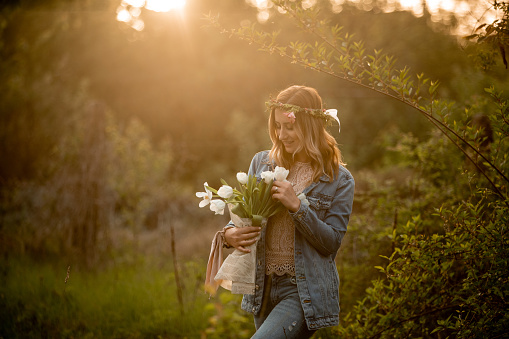 Young woman standing in nature and smeling bouquet of tulips