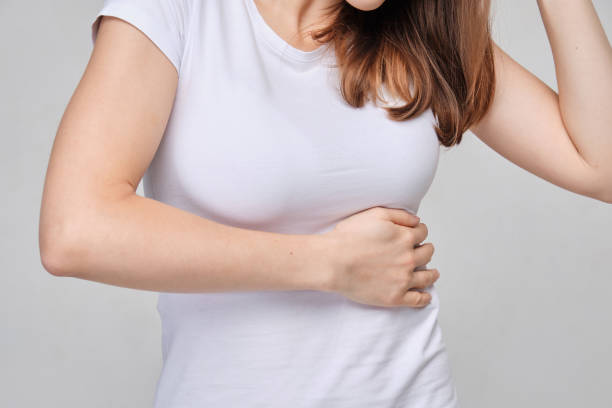 A girl in a white T-shirt massages the left side of the body from pain in the pancreas, spleen. stock photo