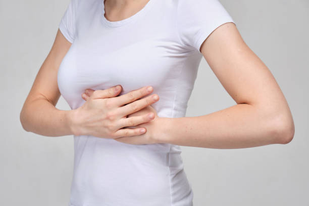 istock A girl in a white T-shirt massages her chest. Breast problems. 1208226574