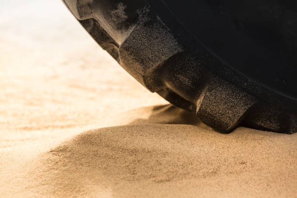 Close up huge heavy tire of tractor on soft ground like beach sand (copy space)
