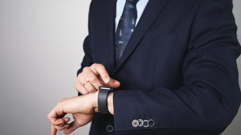 Elegant handsome businessman in a suit using a smartwatch. sharp manager, boss is using a gadget on his hand. Working smart