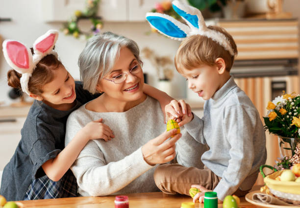 幸せなイースター!家族の祖母と子供の孫は休日のために卵を描きます - adult caucasian senior adult family ストックフォトと画像