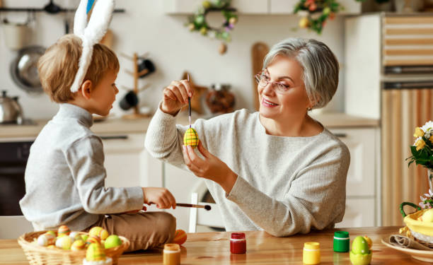 幸せなイースター!家族の祖母と耳を持つ子供は休日の準備をしています - grandmother senior adult family domestic kitchen ストックフォトと画像