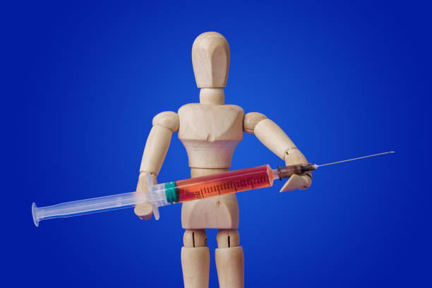 istock Wooden toy figure with syringe on blue 1208239088