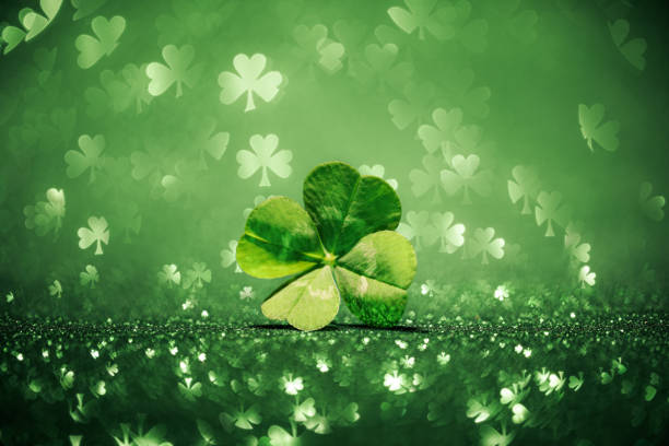 istock Lucky four leaf clover surrounded by sparkling shamrock shapes 1208239505