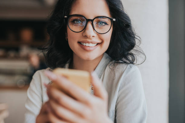 istock Cheerful young woman using smartphone in cafe 1208245593