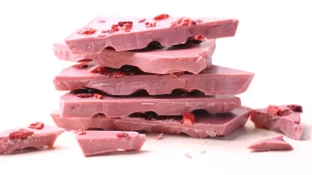 Ruby chocolate, made from botanical cocoa bean varieties that have the right attributes to be processed into ruby chocolate, macro close up on white background.