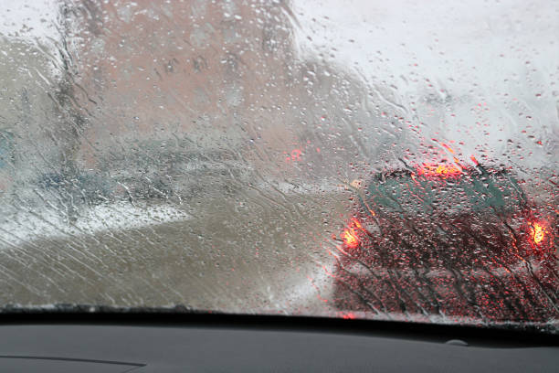 вид с лобового стекла автомобиля во время дождя и мокрого снега. плохая видимость во время вождения по городу. снежная дорога. - sleet стоковые фото и изображения