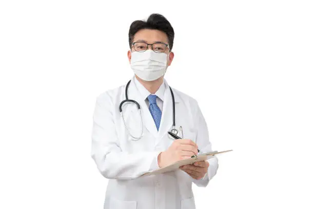 Middle-aged Asian doctor holding clipboard on white background.