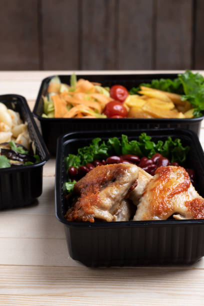 istock fried chicken wings with micro greens, stewed vegetables in food containers 1208254872