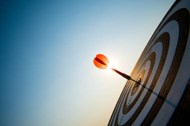 close up shot freccette rosse nel centro di destinazione su sfondo cielo blu scuro. obiettivo aziendale o successo degli obiettivi e concetto di vincitore. - target dart darts aspirations foto e immagini stock