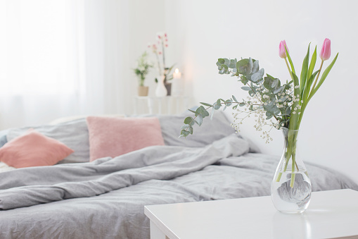pink tulips in vase in cozy bedroom