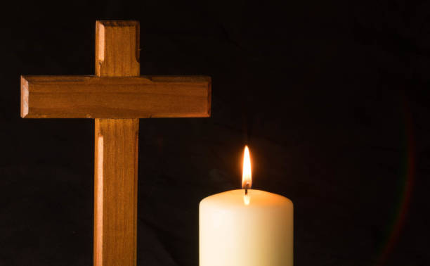 Candle an cross in darkness