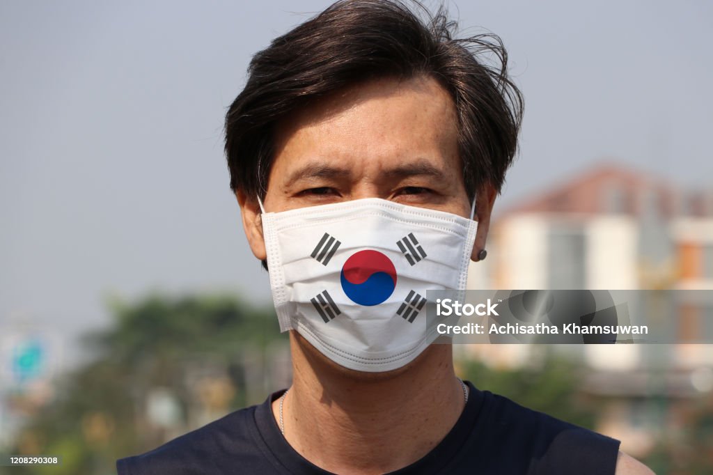 Etelä-Korean lippu hygieenisellä naamiolla. Naamioitunut aasialainen mies estää bakteerit. pienen hiukkassuojauksen käsite. - Rojaltivapaa avainsanalla Korean Tasavalta ja tyyppiä Kuvapankin valokuva