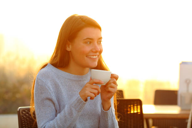 istock Happy girl relaxing drinking coffee at sunset in a cafe 1208292996