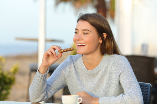 happy girl eating a snack in a cafe terrace - eating women breakfast cereal imagens e fotografias de stock