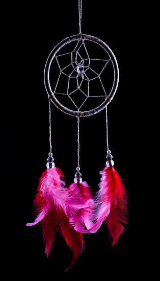 Dreamcatcher with beautiful red-hued feathers on a black background.