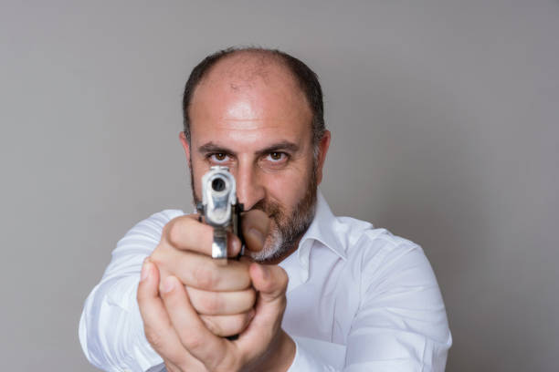 Bold man is pointing a gun directly at the lens